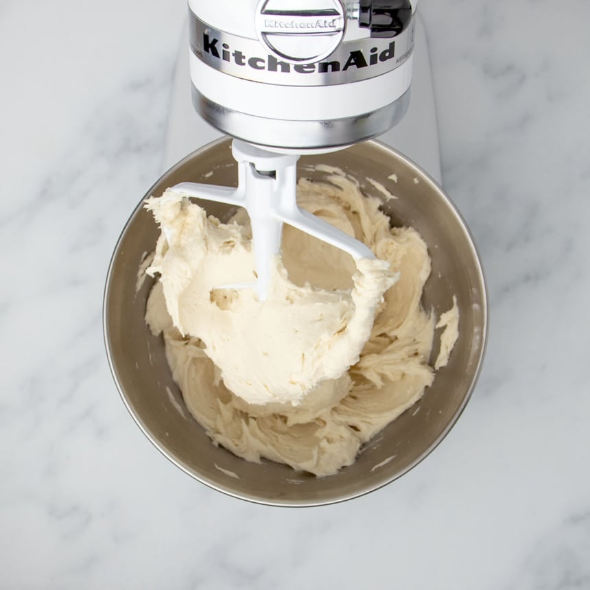 same bowl in white KitchenAid stand mixer with paddle attachment and dough sticking to sides of the bowl and the paddle