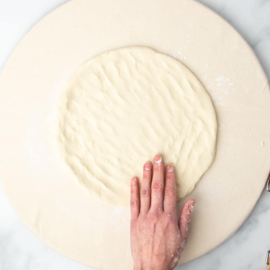 same dough with hand pressing into a thinner, larger round