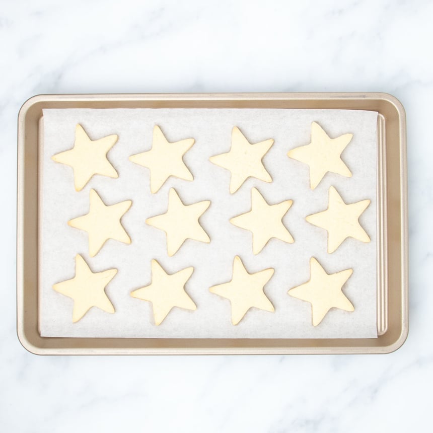 same baking sheet with 12 baked sugar cookie stars