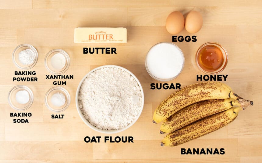 ingredients for oat flour banana bread in small bowls with black block letters spelling out name of each ingredient