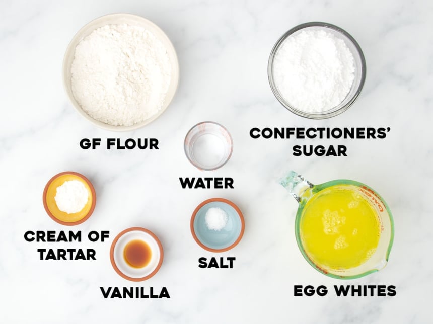 ingredients for gluten free angel food cake in small bowls with black block letters spelling name of each ingredient