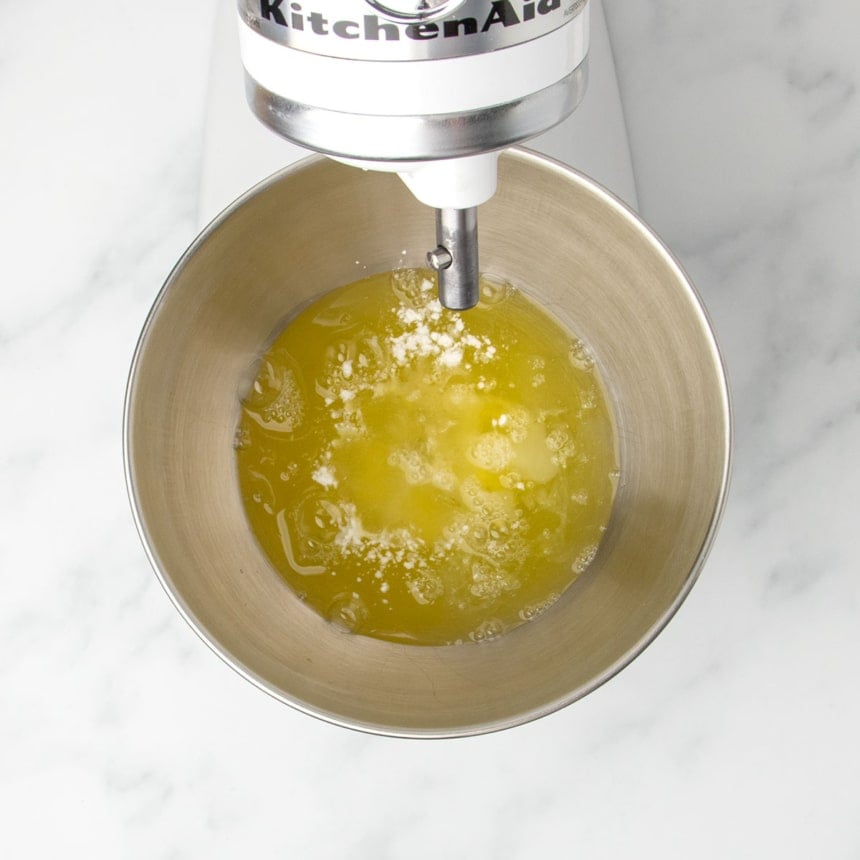 white stand mixer with round metal mixing bowl with egg whites and cream of tartar