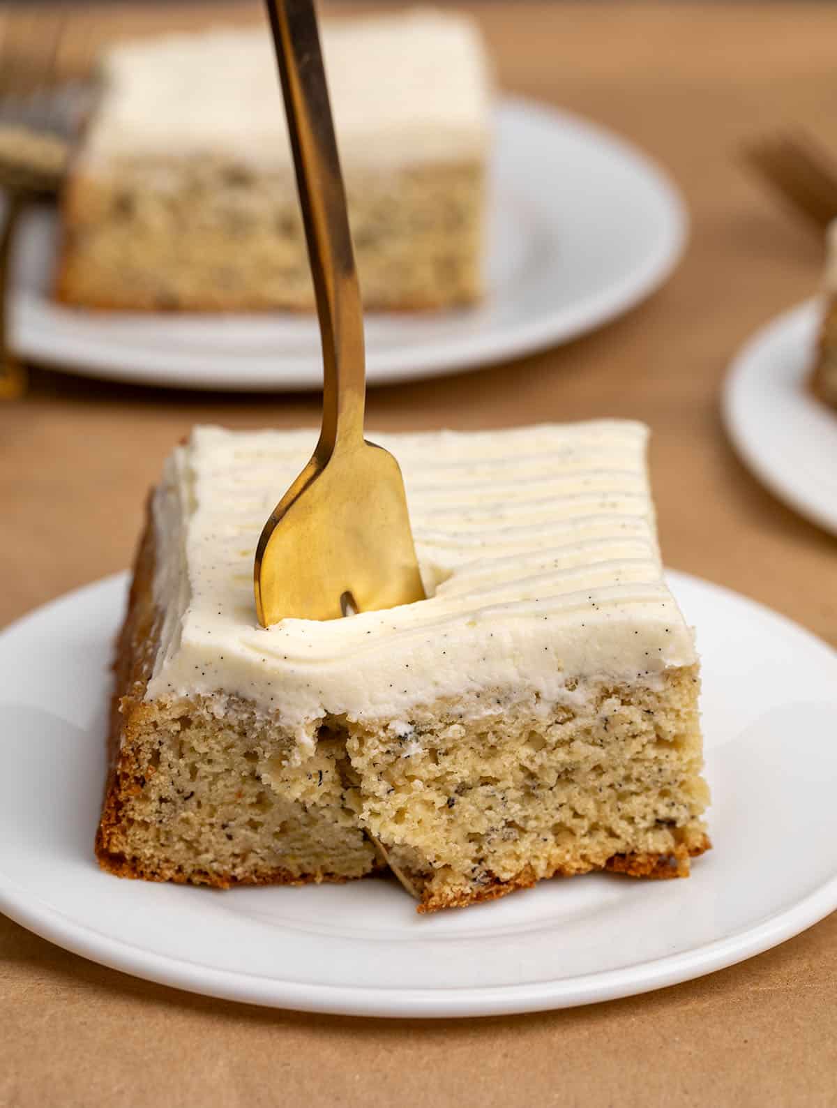 Gold fork piercing square slice of yellow banana cake .