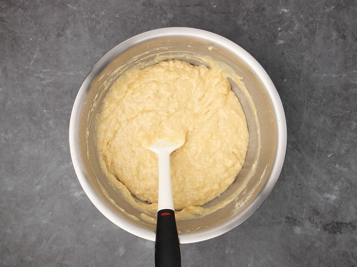 soft light yellow cake batter with dry ingredients now mixed in, still with white spatula in the bowl