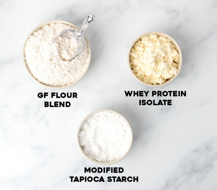 ingredients for gluten free bread flour in 2 small round bowls white powder and 2 small round bowl with light yellow powder with black block letters spelling out name of each ingredient