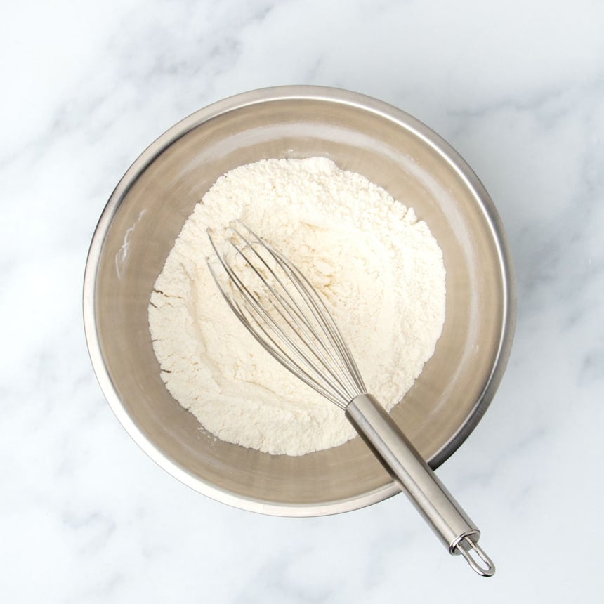 same bowl with pale white-tan powder whisked together with large metal wire whisk