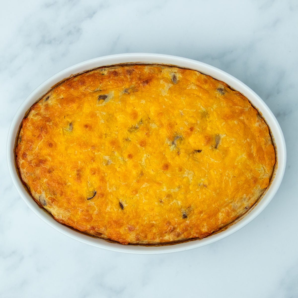 overhead image of white casserole dish with orange and browned melted cheese on top of cooked casserole