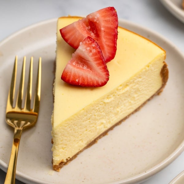 slice of cheesecake with one strawberry cut in half