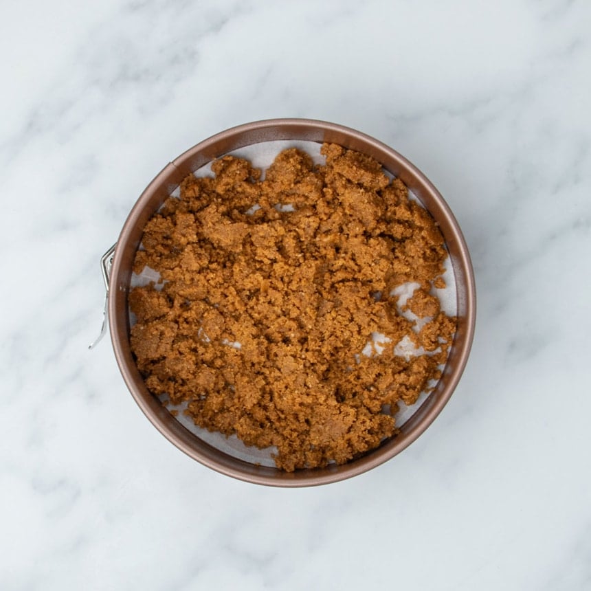 same brown clumps in round gold colored springform pan with white parchment paper lining