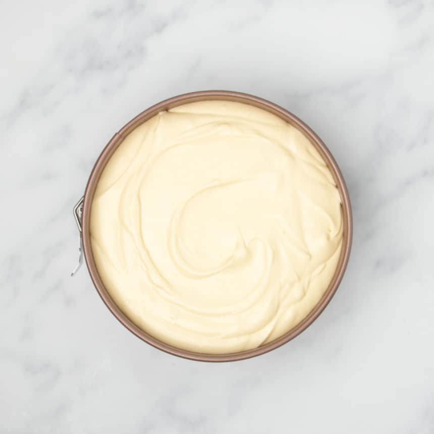 light yellow raw cheesecake mixture in gold colored round springform pan