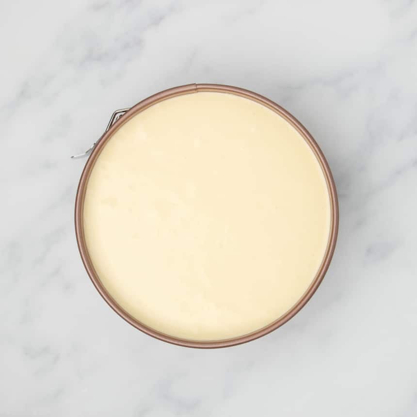light yellow raw cheesecake mixture in same pan smoothed out into even layer