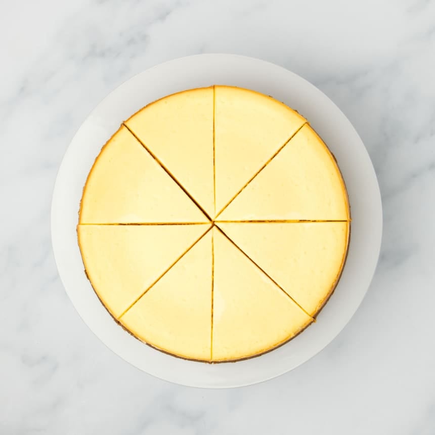 same baked cheesecake out of pan sliced into 8 triangles on a white plate