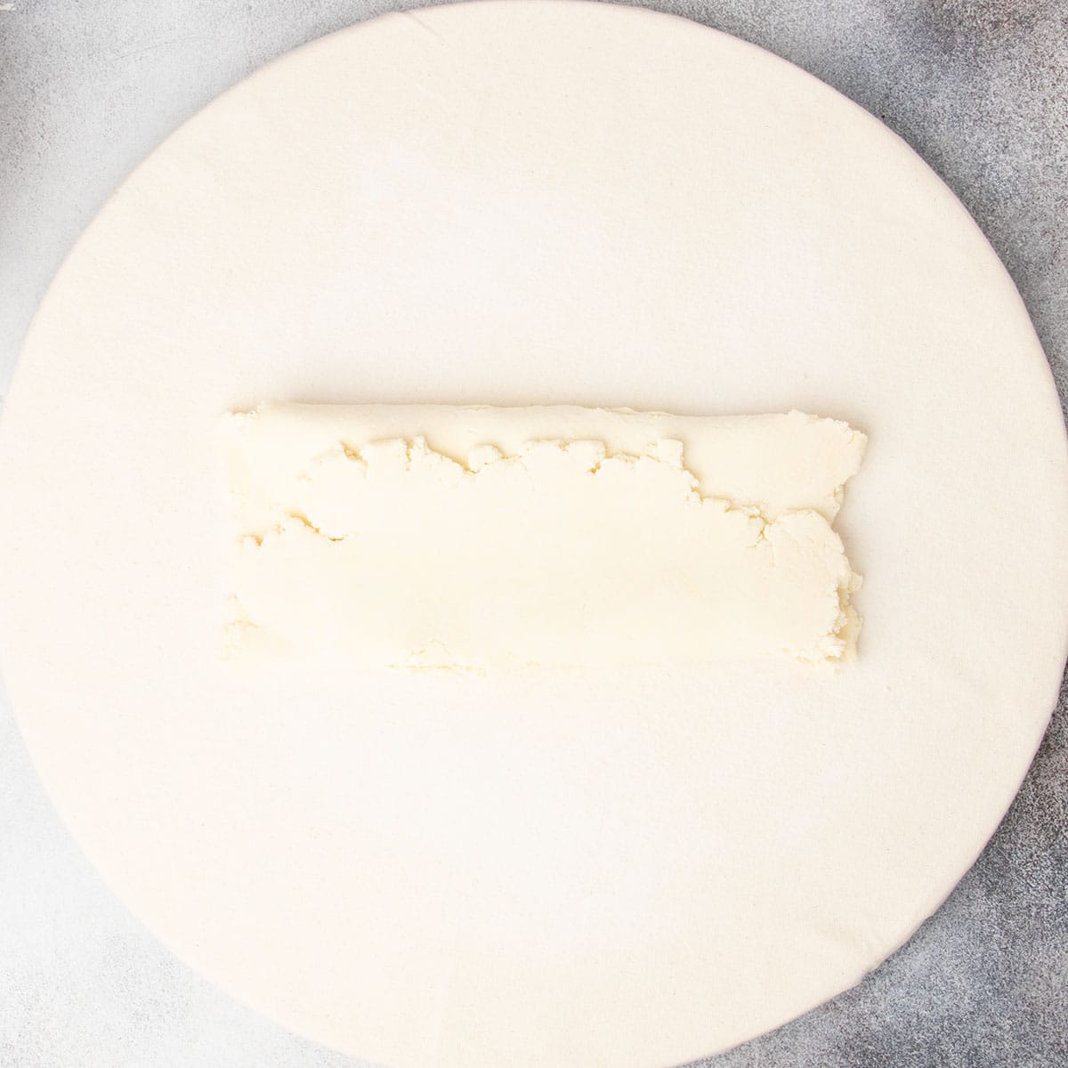 Rough raw pastry rectangle folded in thirds like a business letter on board.