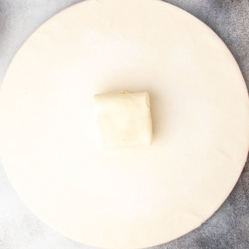 square of rolled and folded raw dough on pastry board