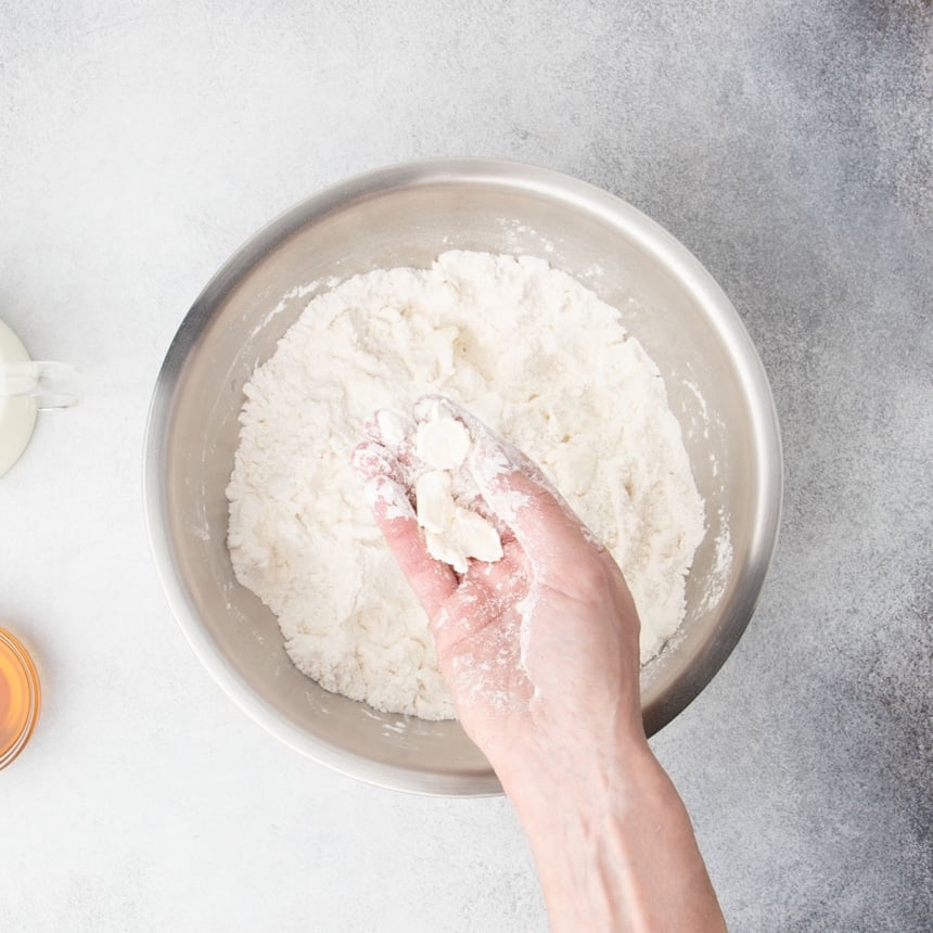 Cutting cold butter into gluten free flour with fingers in a metal mixing bowl