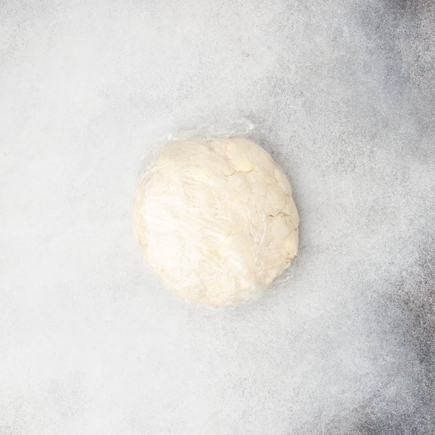 tan scone dough wrapped in plastic wrap and ready to chill