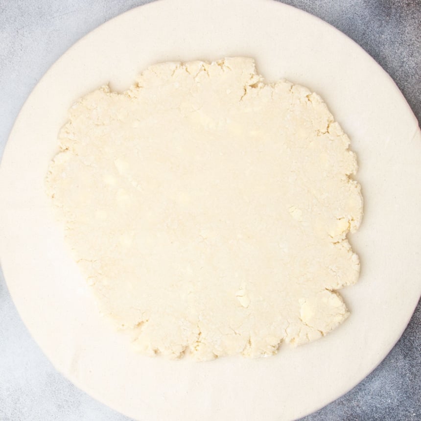 tan scone dough rolled out into a rough round on a tan round cloth