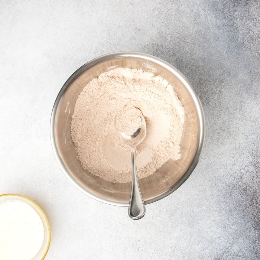 Brown sugar, cinnamon, and flour mixture stirred together in a metal mixing bowl with a metal mixing spoon