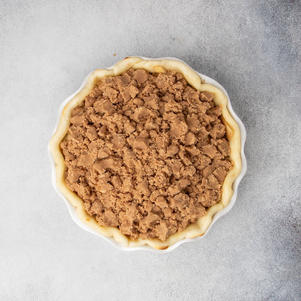 Unbaked apple pie filled with seasoned apples and topped with a crumb mixture. 