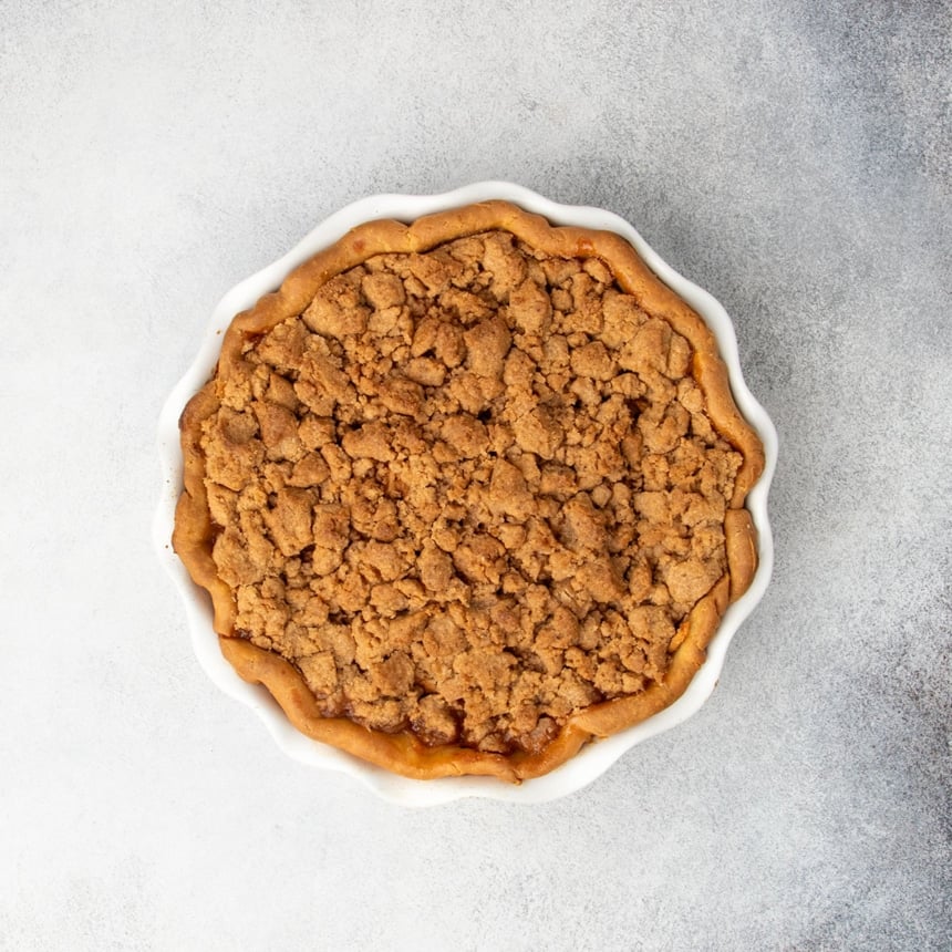 Golden brown fully baked apple pie with a crisp browned crumble topping, just out of the oven.