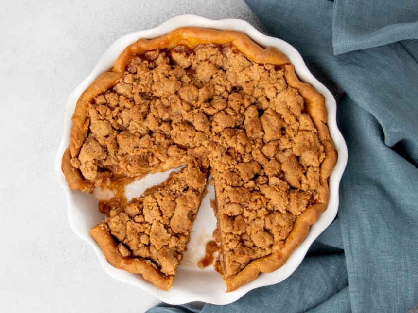 Gluten free apple pie with a wedge-shaped slice removed to reveal the tender spiced filling.