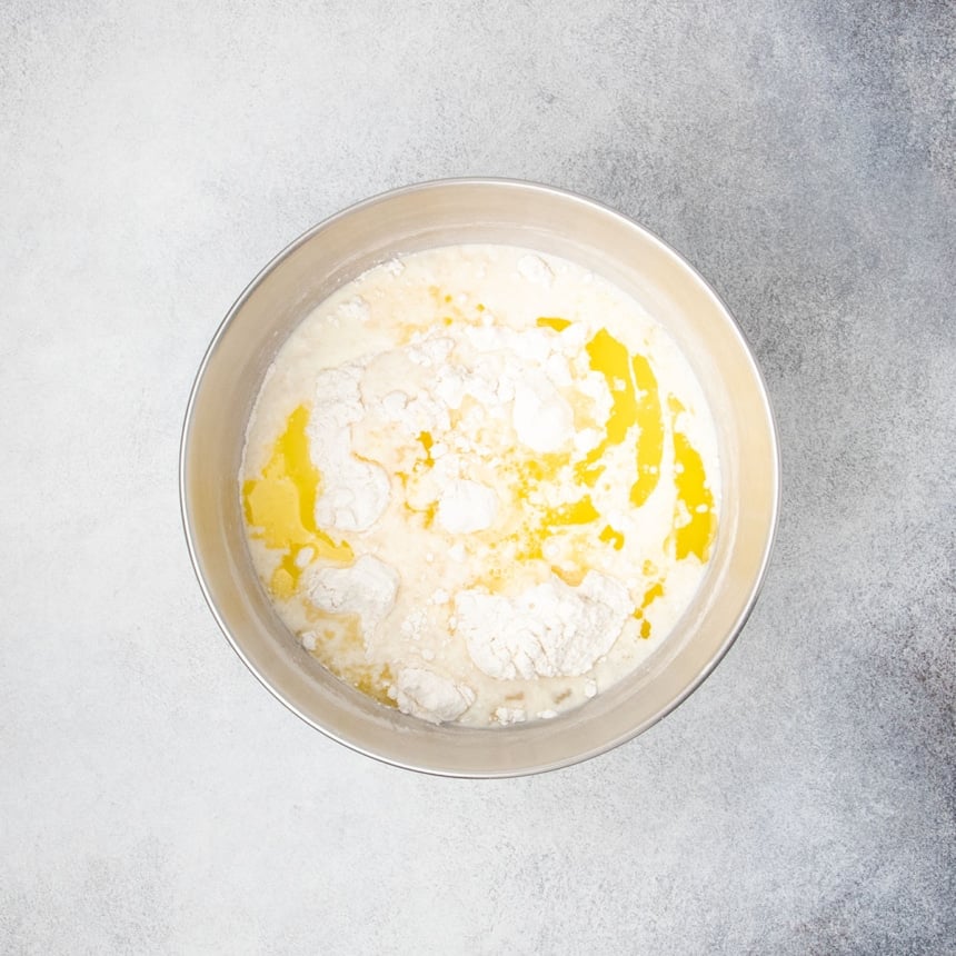 Butter, milk, and egg whites added to the flour mixture in a metal bowl before mixing.
