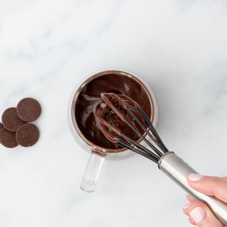 Chocolate batter being whisked until smooth inside the mug.