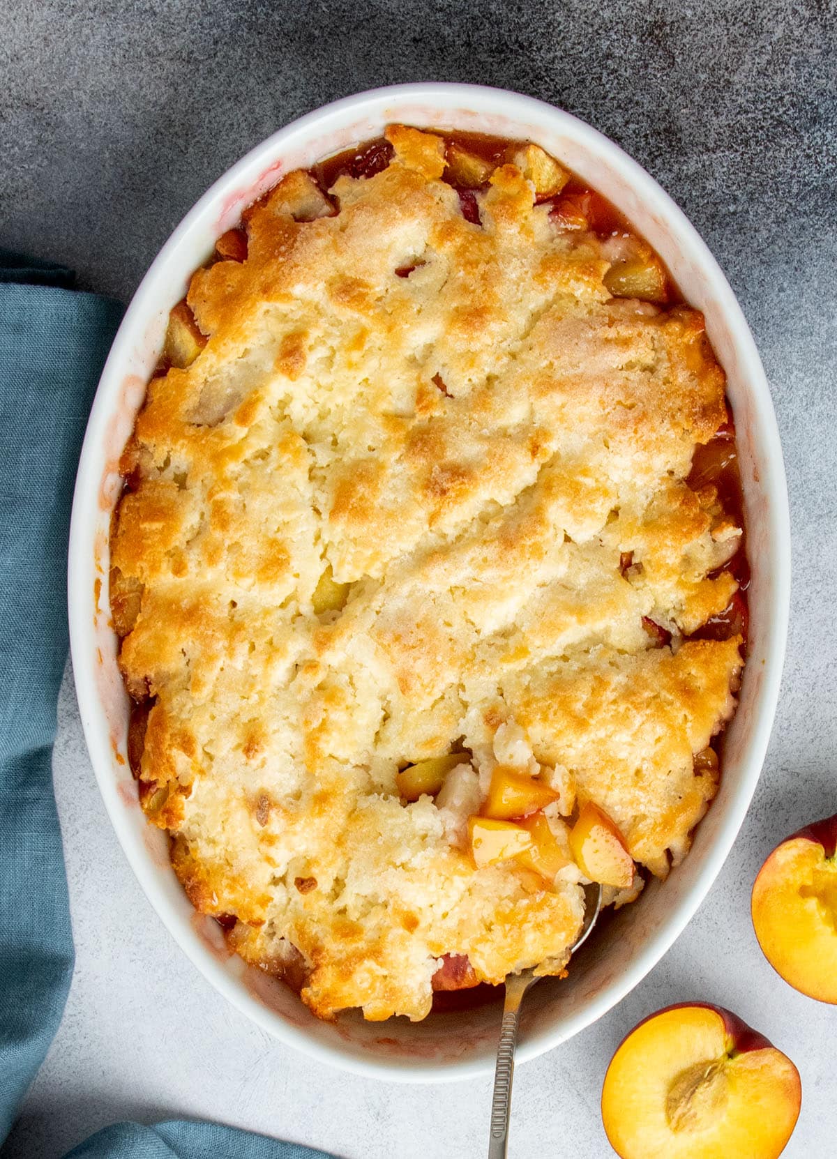 Overhead view of a freshly baked gluten free peach cobbler with crisp golden topping and bubbling fruit at the edges.