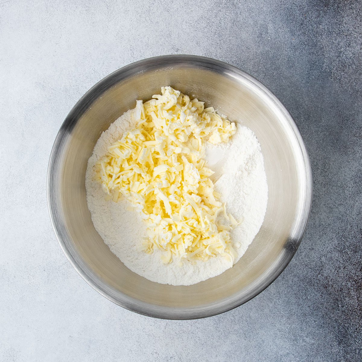 Grated butter added to a bowl of gluten free flour in the first step of making the cobbler topping