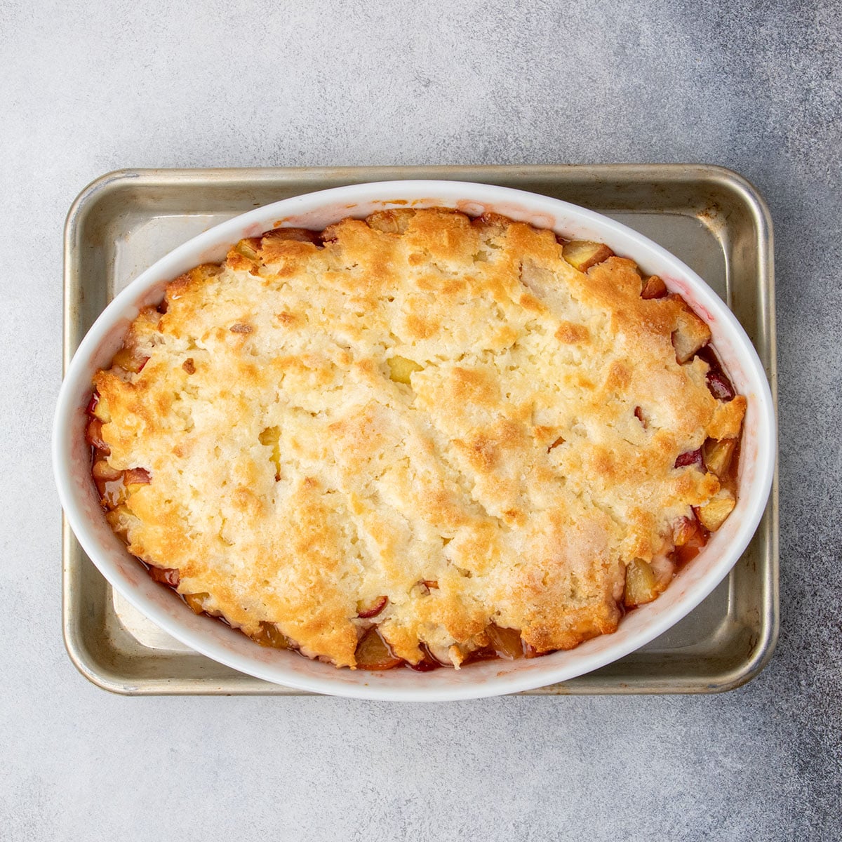 Gluten free peach cobbler fresh from the oven, with a golden brown, crisp topping and bubbling peach filling around the edges.
