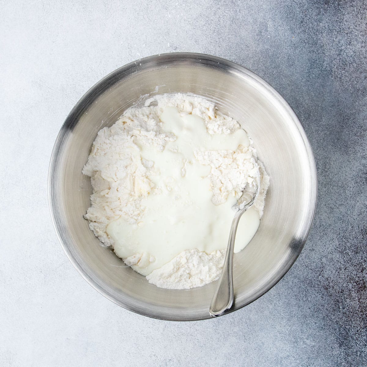 Buttermilk added to the flour and butter mixture in a large mixing bowl for the cobbler topping.
