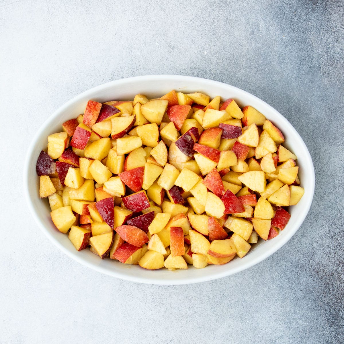 Tossed filling spread evenly in a white oval baking dish.