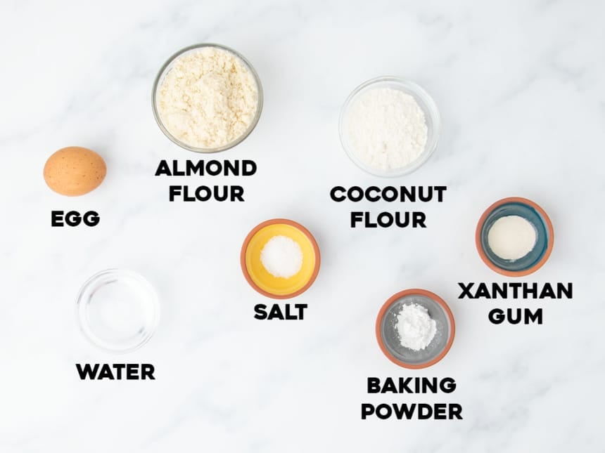Labeled ingredients for almond flour tortillas arranged on a white marble surface