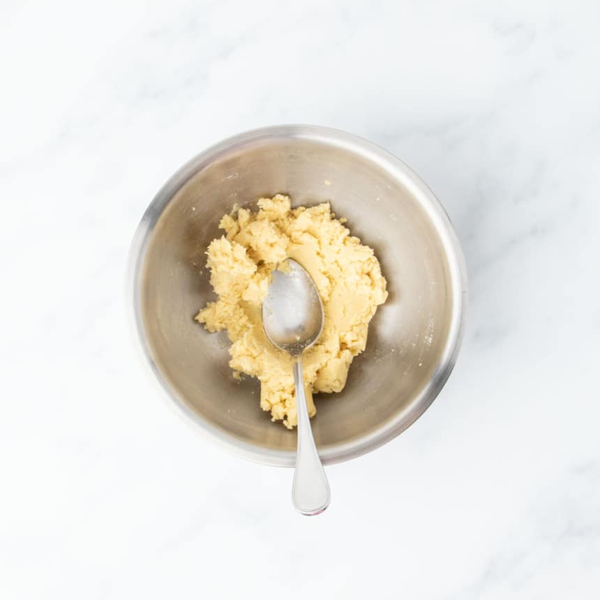 Mixed dough for tortillas in a metal bowl with a spoon