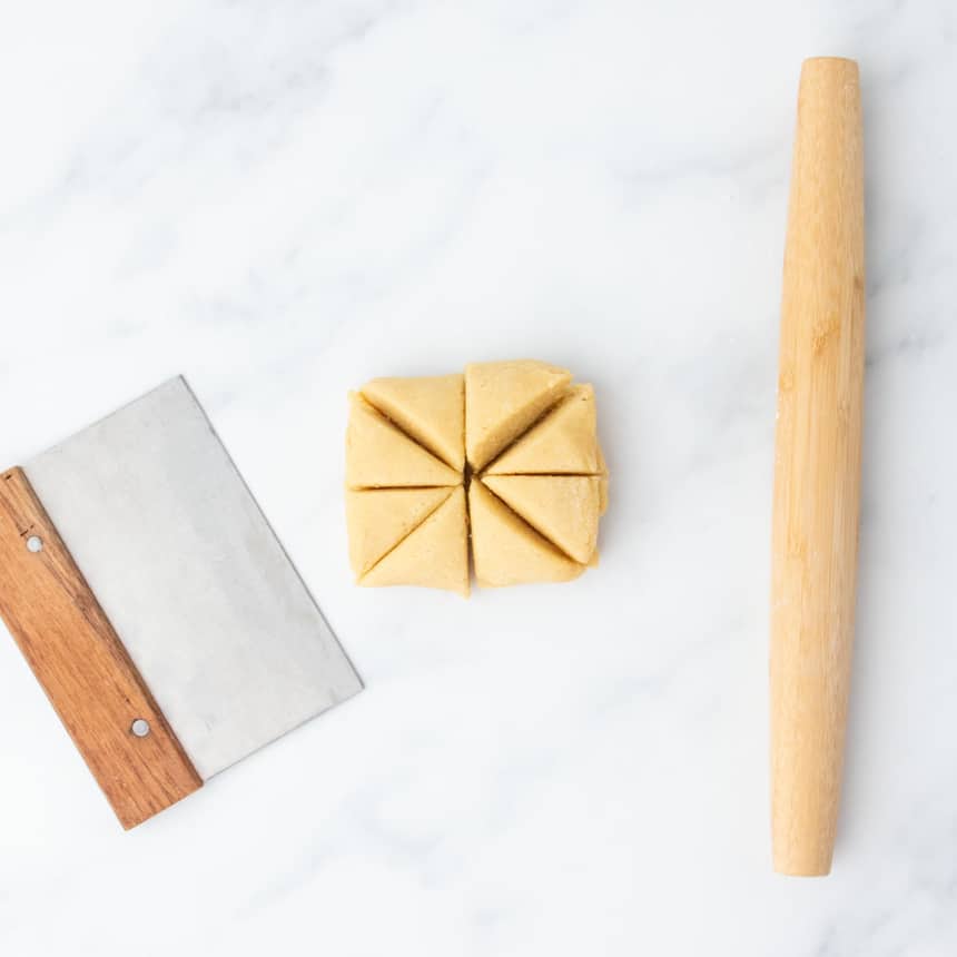 Dough divided into 8 wedges with a bench scraper beside it