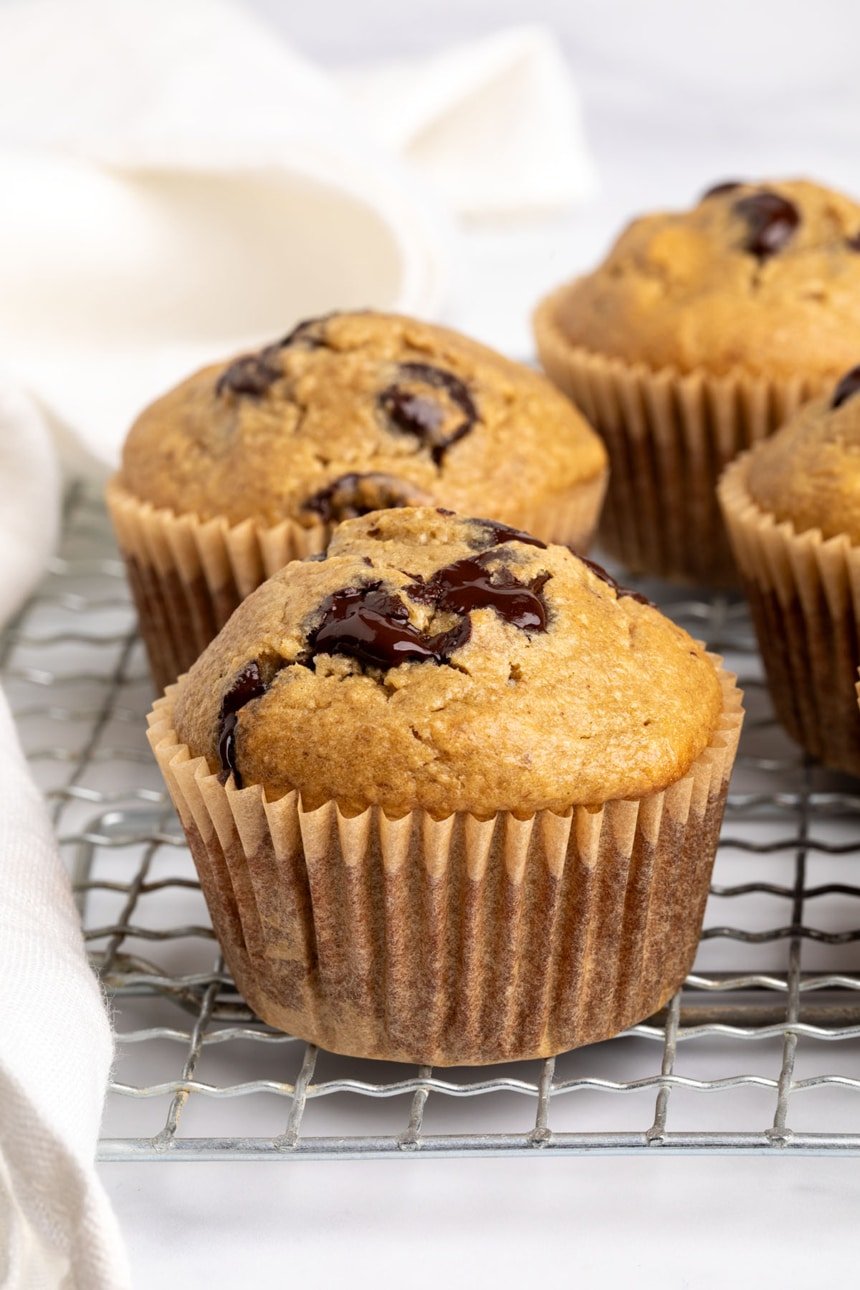 A few muffins resting on a cooling rack, with soft centers and golden edges