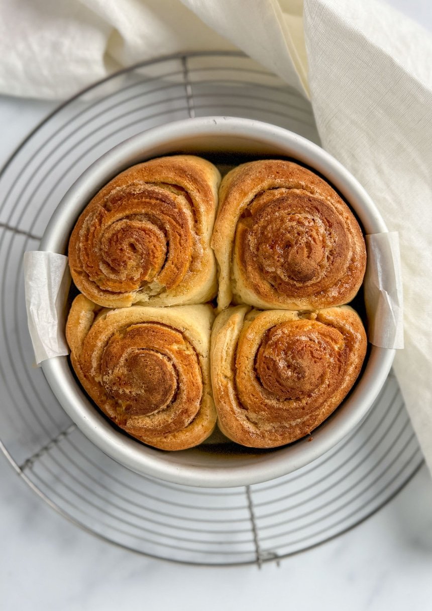 4 gluten free cinnamon rolls using psyllium husk with xanthan gum in round metal cake pan on wire rack