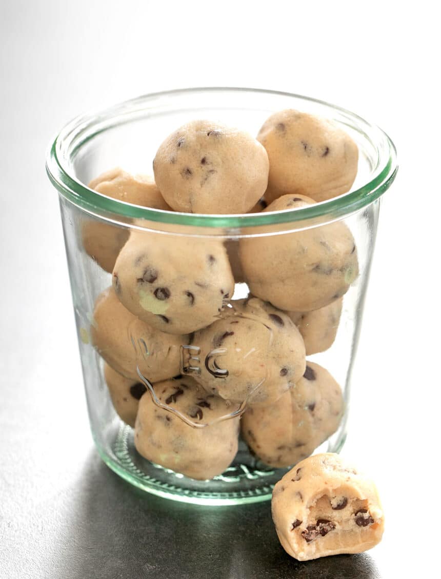 glass mason jar with light brown gluten free edible cookie dough balls on black surface