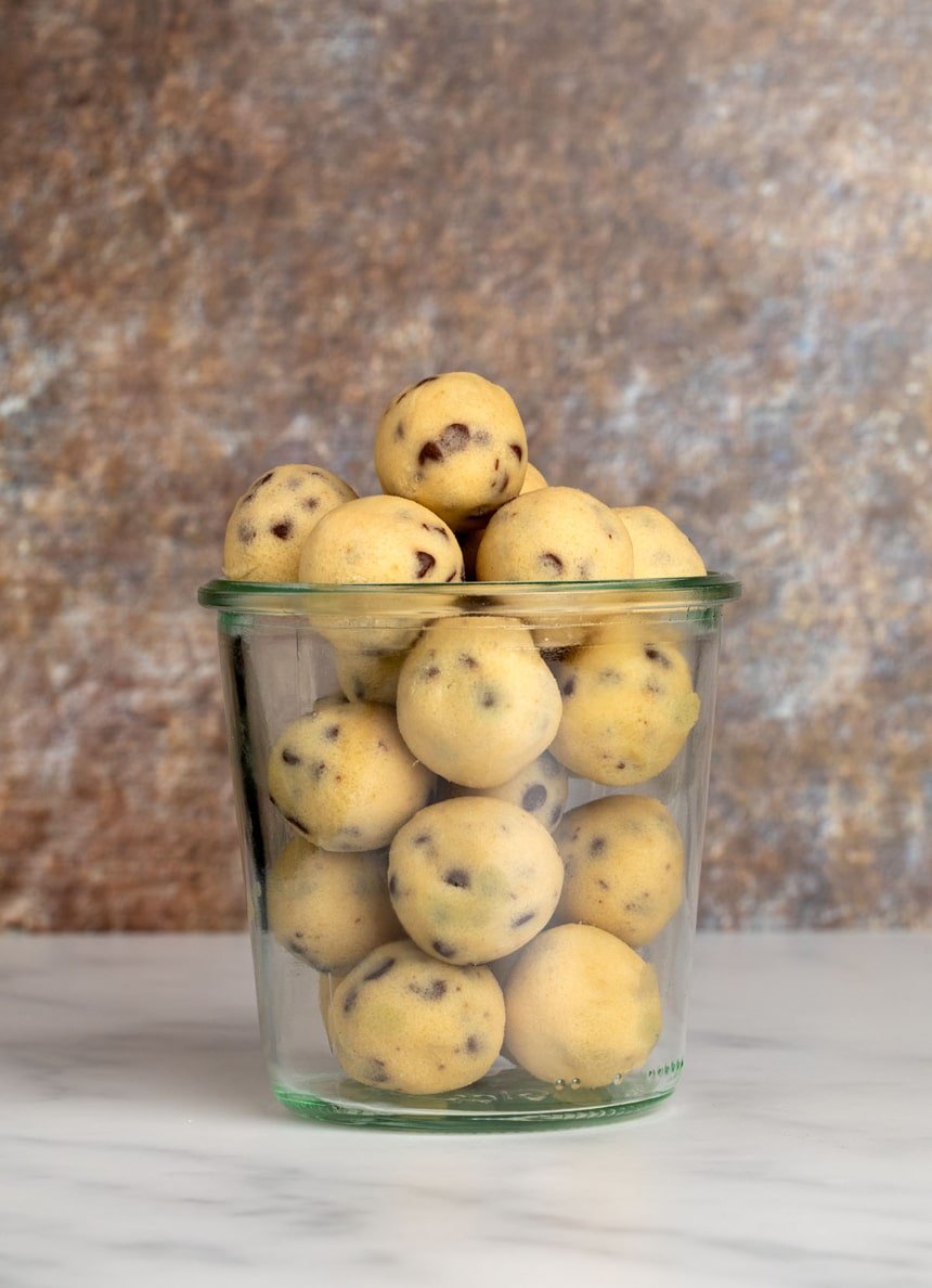 Glass jar filled with neatly rolled balls of gluten free cookie dough, ready for snacking.