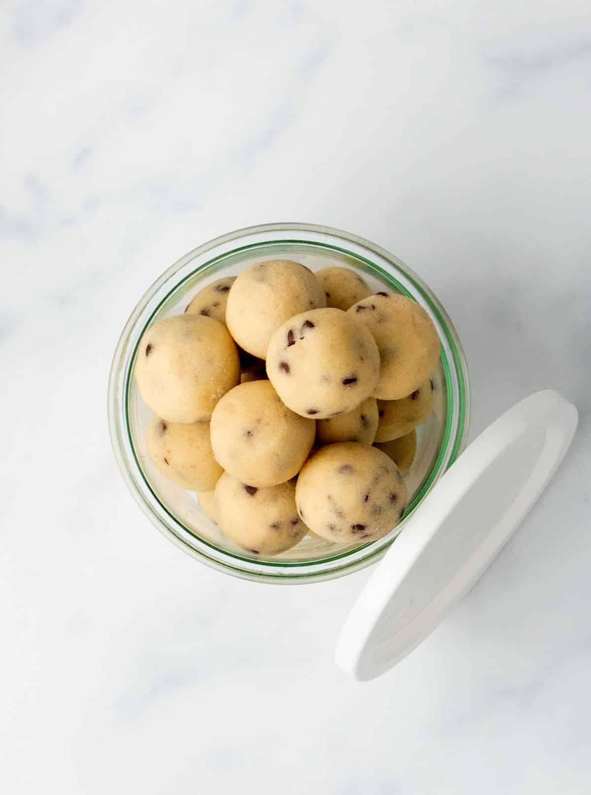 Top-down view of a glass jar filled with chocolate chip cookie dough balls.