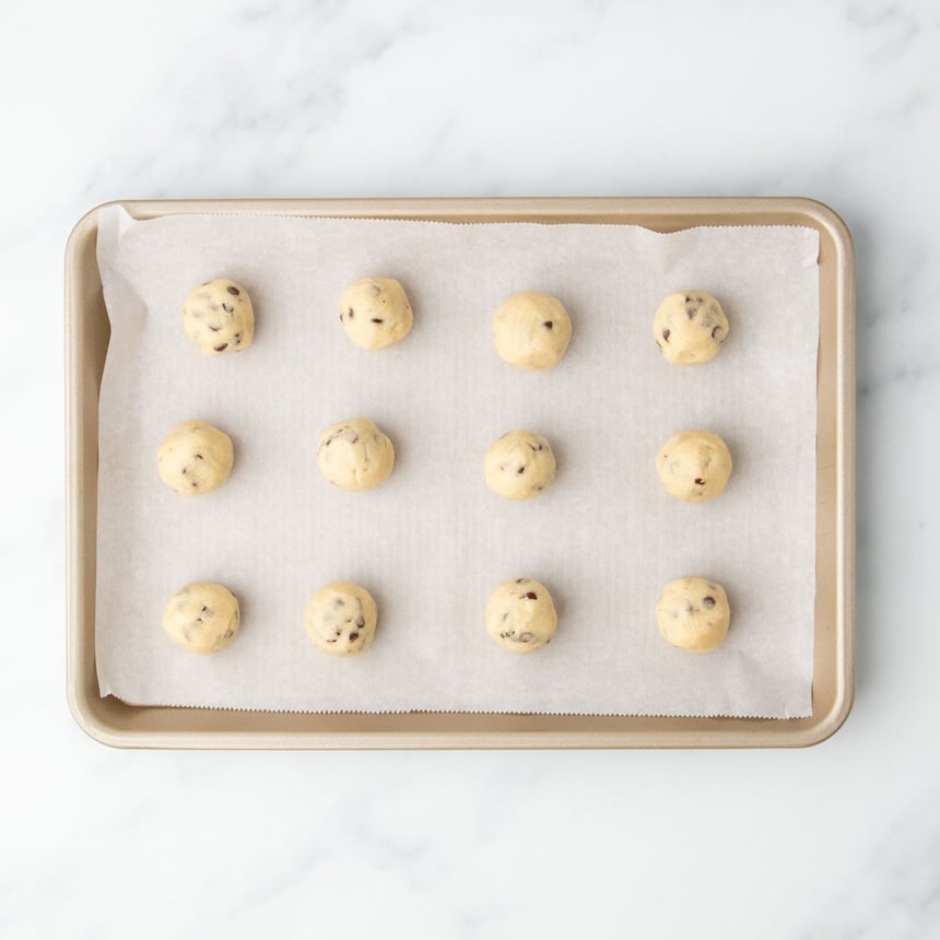 Neatly formed gluten free cookie dough portions arranged on a baking tray.