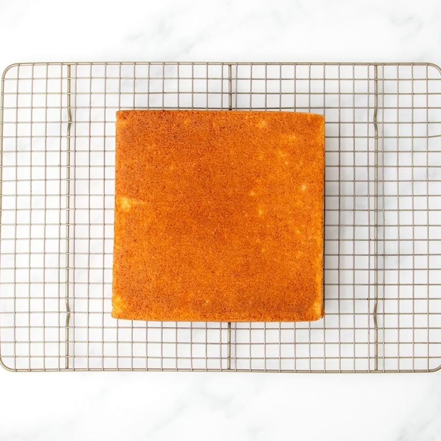 Golden baked square cake resting upside down on a wire cooling rack, just removed from the pan and cooling completely.