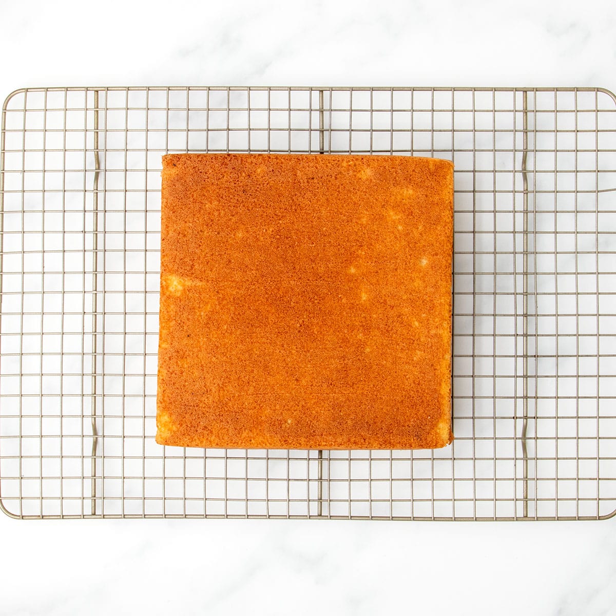 Golden baked square cake resting upside down on a wire cooling rack, just removed from the pan and cooling completely.