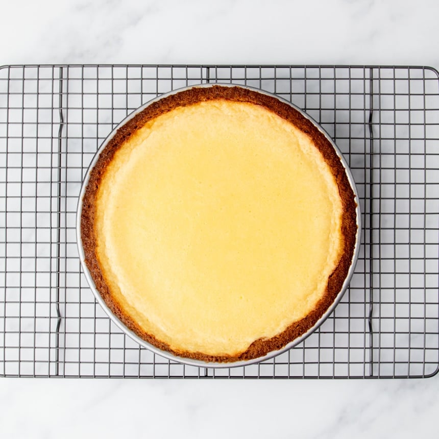 Fully baked lemon pie cooling on a wire rack, with a lightly golden top and crisp crust edges.