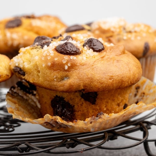 Close-up of a chocolate chip muffin on a cooling rack, wrapper peeled back to show the tender crumb