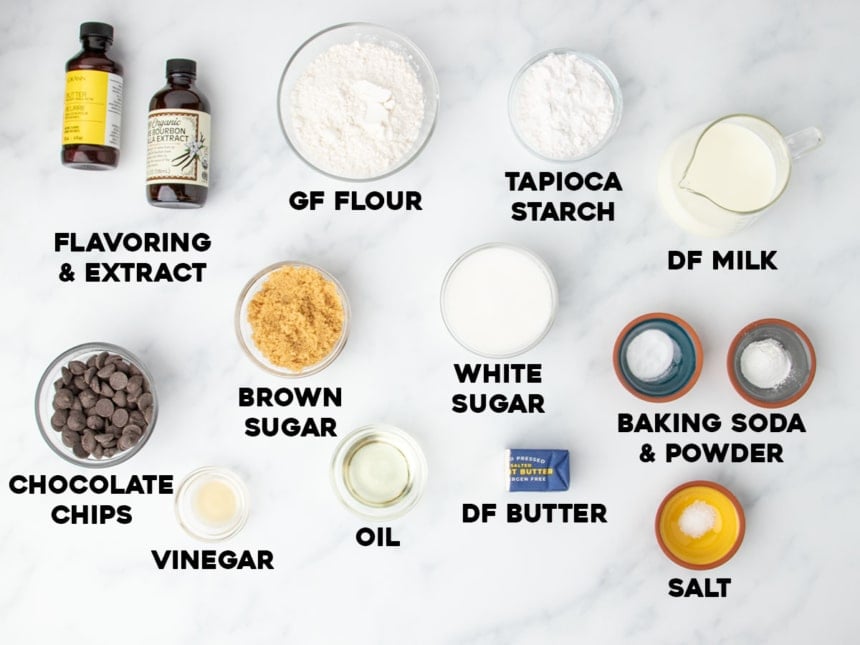 Overhead view of ingredients measured out for gluten free vegan muffins, including gluten free flour, dairy free milk and butter, oil, chocolate chips, and flavoring extracts