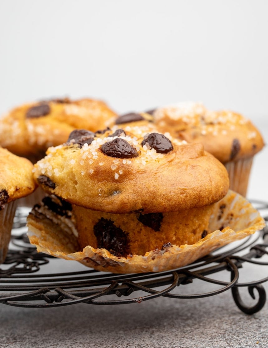 Close-up of a chocolate chip muffin on a cooling rack, wrapper peeled back to show the tender crumb