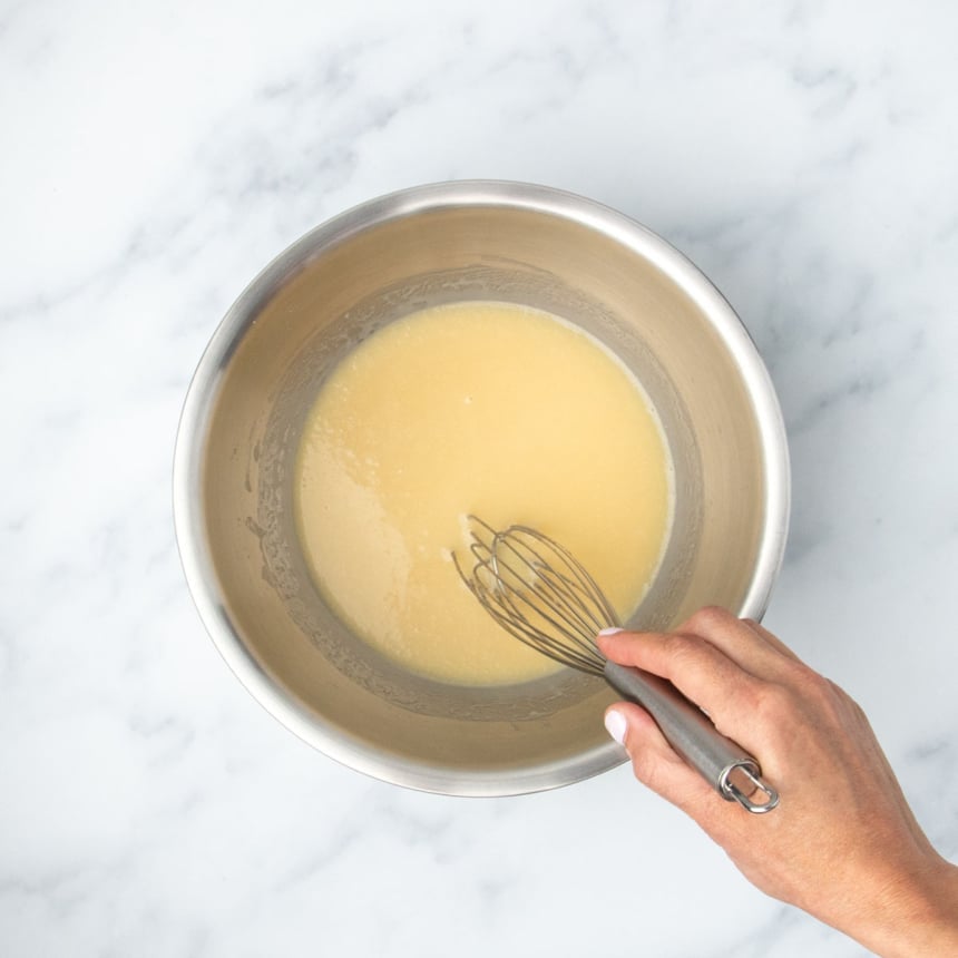 Whisking together sugar and wet ingredients until well combined and smooth.