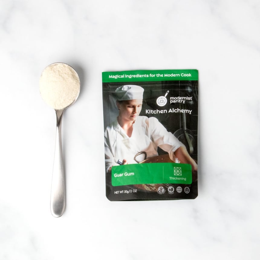 black and green pouch of guar gum with sample of white powder on large metal spoon