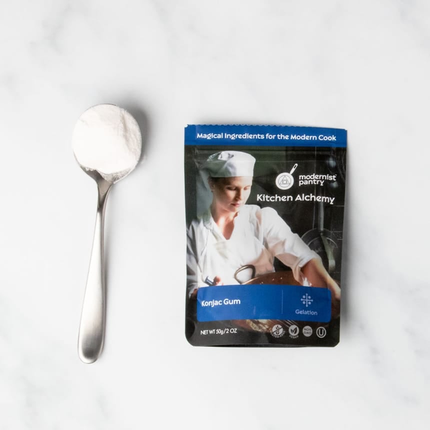 black and bluepouch of konjac powder with sample of white powder on large metal spoon